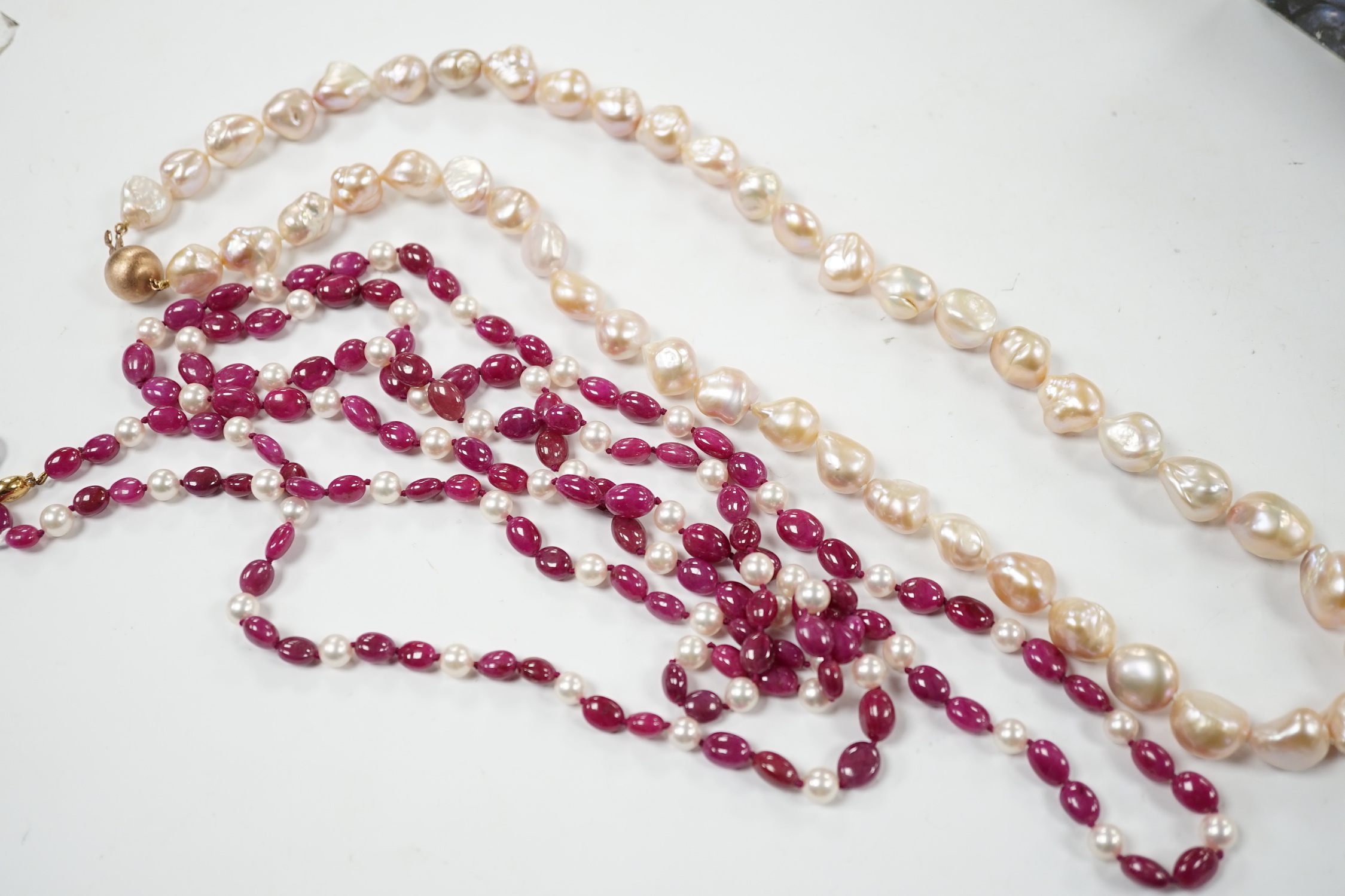 A modern cultured pearl and polished ruby? bead necklace, with two stone diamond chip set 750 clasp, 166cm and a modern baroque freshwater? pearl necklace with 925 clasp.